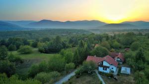 una casa en una colina con la puesta de sol en el fondo en Guest house Jandric, en Drežnik Grad