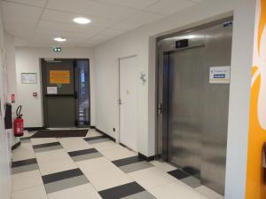 - un couloir avec deux portes et du carrelage dans l'établissement Premiere Classe Le Havre Centre-LES DOCKS, au Havre