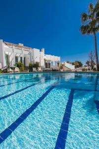 einen Pool mit blauem Wasser und einer Palme in der Unterkunft Villa Capricho in Marbella