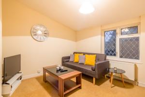 a living room with a couch and a clock on the wall at Skyline Serviced Apartments - Colestrete in Stevenage