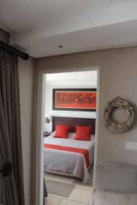 - une chambre avec un lit et des oreillers rouges dans l'établissement Seafront Apartment in Mossel Bay, à Mossel Bay