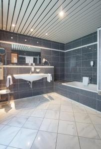 ein Badezimmer mit einer Badewanne, einem Waschbecken und einem Badetubermott in der Unterkunft Hotel Stadt Breisach in Breisach am Rhein