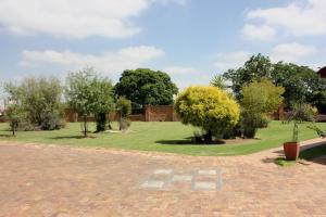 a park with a bench and trees and grass at The Lazy Grape Guest Lodge & Spa in Benoni
