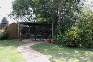 a patio with a table and chairs in a garden at The Lazy Grape Guest Lodge & Spa in Benoni
