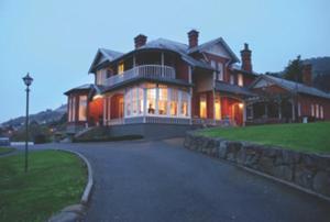 ein großes Haus mit einer Steinmauer in der Unterkunft St Leonards Lodge in Dunedin