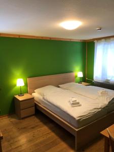 ein Schlafzimmer mit einem Bett mit einer grünen Wand in der Unterkunft Auerhahn in Feldberg