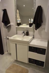 a white bathroom with a sink and a mirror at Apartment Fine Living 122 in Vršac