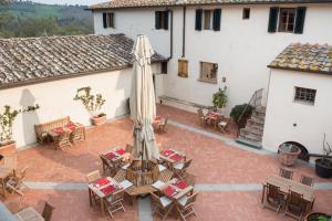 an outdoor patio with tables and chairs and an umbrella at Fattoria di Rignana in Greve in Chianti