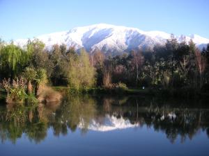 a snow covered mountain is reflected in a lake at Donegal House in Kaikoura
