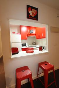 a small kitchen with red cabinets and red stools at Apartamento Puerto-Terol in Alicante