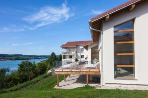 een huis met een terras en uitzicht op het water bij Hotel Spa Les Rives Sauvages in Malbuisson