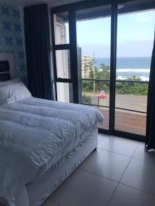 a bedroom with a bed and a view of the ocean at Toti Oasis Holiday Apartments in Amanzimtoti