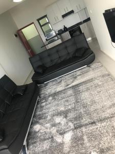 a living room with a black couch and a rug at Toti Oasis Holiday Apartments in Amanzimtoti