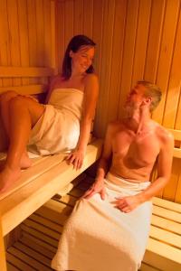 um homem e uma mulher sentados numa sauna em Etno House Gosteče- Suite with Finnish sauna em Mozirje
