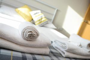 una pila de toallas sentadas encima de una cama en Portland Square - 2 Bedroom Modern City Apartment en Nottingham