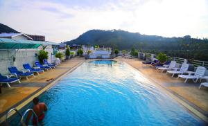 a large swimming pool with lounge chairs and chairs at Arita Hotel Patong in Patong Beach