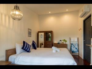 Un dormitorio con una gran cama blanca y una lámpara de araña. en 18 In Town Homestay, en Chiang Mai