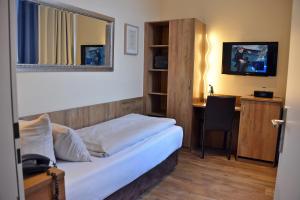 a bedroom with a bed with a desk and a mirror at Arthotel Munich in Munich