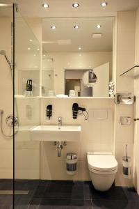 a bathroom with a sink and a toilet and a mirror at Arthotel Munich in Munich