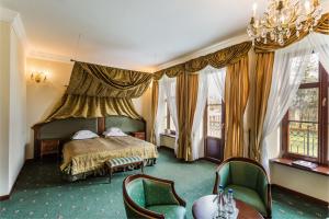 a bedroom with a bed and some chairs and windows at Dwór Kombornia Hotel&SPA in Kombornia