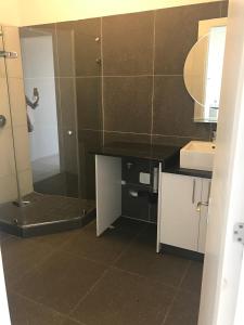 a bathroom with a shower and a sink and a mirror at Toti Oasis Holiday Apartments in Amanzimtoti