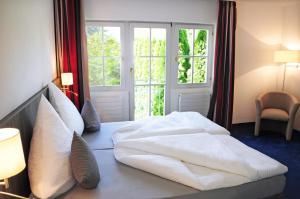 1 dormitorio con 1 cama con sábanas blancas y ventana en Hotel Krone Überlingen am Ried, en Singen