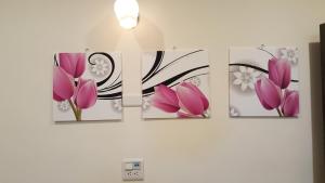 three panels of pink flowers on a wall at Long Yuan Hotel in Budai