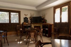 a dining room with tables and chairs and a tv at Hotel Rural Santa Inés in Vinuesa