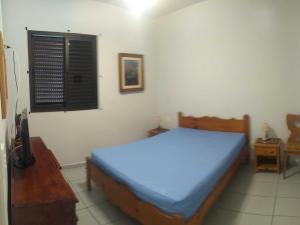 a bedroom with a blue bed and a window at Apartamento em Ubatuba próximo a praia! in Ubatuba