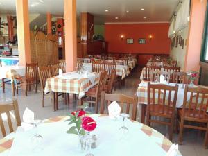 un restaurante con mesas blancas y sillas con flores. en Residencial Familia en Machico