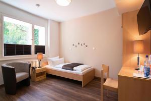 een slaapkamer met een bed, een stoel en een raam bij Hotel Morgenland in Berlijn
