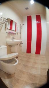 a bathroom with a toilet and a red and white striped wall at Long Yuan Hotel in Budai