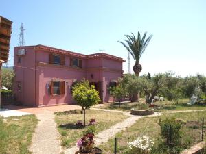 una casa rosa con una palma di fronte di Villa Serro a Villafranca Tirrena
