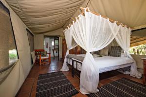 - une chambre avec un lit à baldaquin et une moustiquaire dans l'établissement Pungwe Safari Camp, à Domaine de chasse de Manyeleti