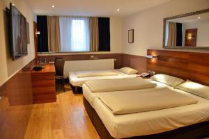 a hotel room with two beds and a mirror at Arthotel Munich in Munich