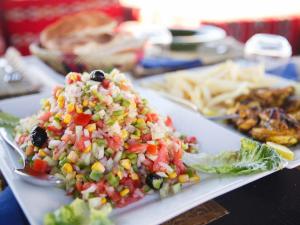 a plate of food with corn salsa and vegetables at Nubia Luxury Camp Erg Chegaga in El Gouera