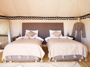El GoueraにあるNubia Luxury Camp Erg Chegagaのテント内のベッドルーム1室(ベッド2台付)