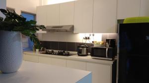 a kitchen with white cabinets and a microwave at INFA - Muslim House @ Seroja Apartment, Johor Bahru in Johor Bahru