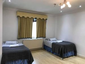 1 dormitorio con 2 camas y ventana en Mapesbury Hostel London, en Londres