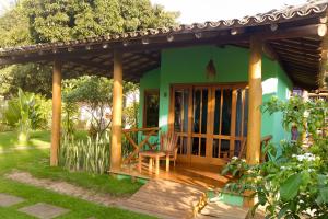 a green house with a wooden porch with a table at Pousada Denada in Barra Grande