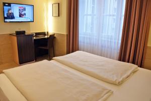 a hotel room with a bed and a desk and a television at Arthotel Munich in Munich