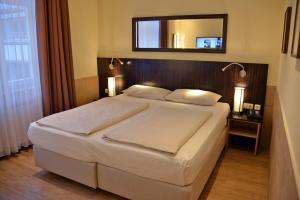 a bedroom with a large bed with a mirror above it at Arthotel Munich in Munich