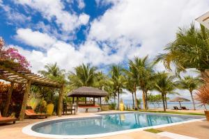 a pool at the resort with palm trees at Pousada Denada in Barra Grande