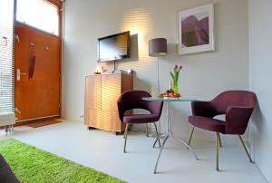 アムステルダムにあるイースタンドロームのテーブル、椅子2脚、テレビが備わる客室です。