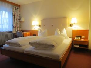 um quarto de hotel com uma cama grande com almofadas brancas em Hotel Cebulj em Bad Wörishofen