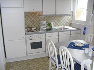 uma cozinha com armários brancos e uma mesa com cadeiras em Assmanns Ferienwohnungen Ost em Miltenberg