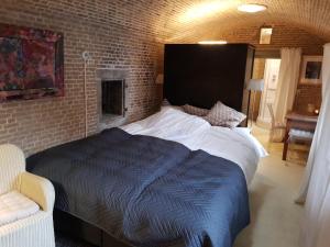 1 dormitorio con 1 cama grande y pared de ladrillo en Kazemat Zus, en Woudrichem