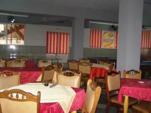 una sala da pranzo con tavoli, sedie e tende rosse di El Stefano Srl a Cavnic