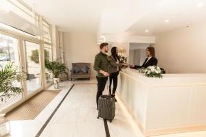 mężczyzna i kobieta z walizką w holu hotelowym w obiekcie Villa Bravo & SPA w mieście Międzyzdroje