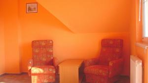 バラトンボグラールにあるLala Apartmanokのオレンジ色の壁の客室で、椅子2脚とテーブル1台が備わります。